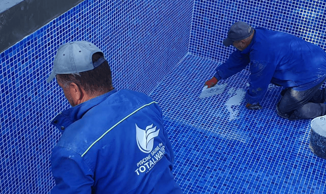 Doi muncitori Total Water montează mozaic albastru într-o piscină